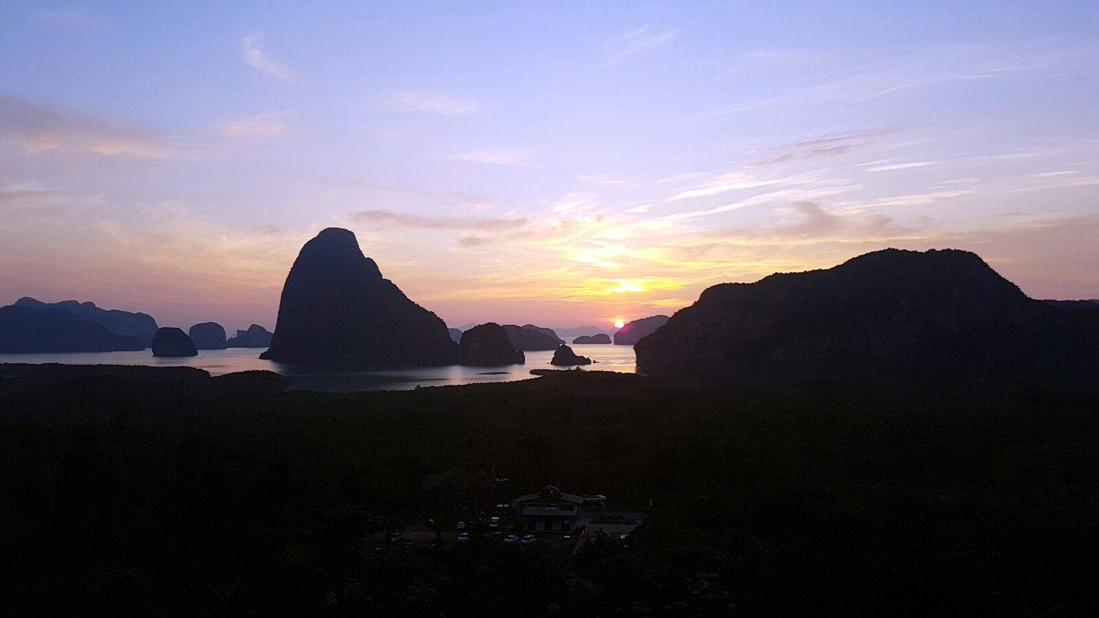 Limestone karsts of Phang Nga Bay silhouetted against a golden dusk sky